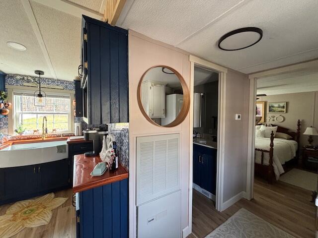 hallway featuring a sink, a textured ceiling, baseboards, and wood finished floors