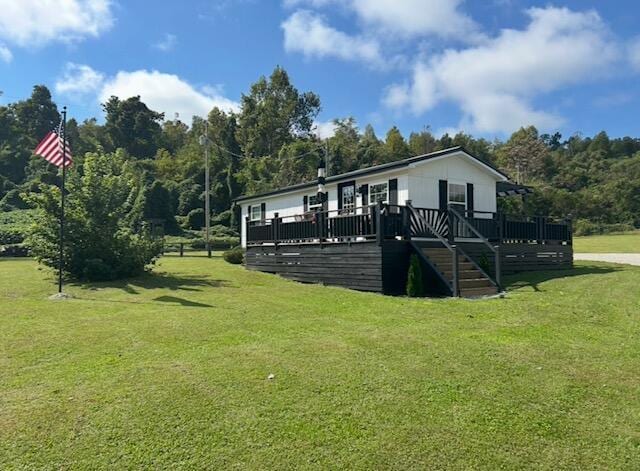 exterior space with stairs, a lawn, and a wooden deck