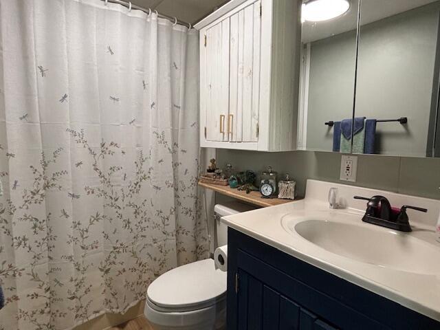 full bathroom with a shower with shower curtain, toilet, and vanity