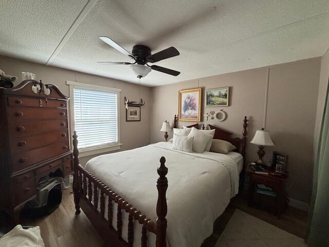 bedroom with ceiling fan, a textured ceiling, and wood finished floors