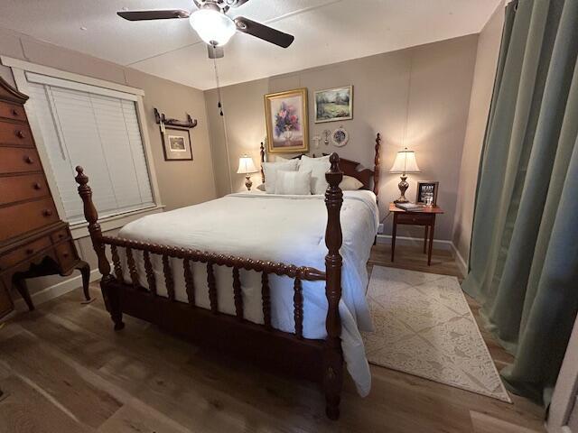 bedroom featuring ceiling fan, baseboards, and wood finished floors