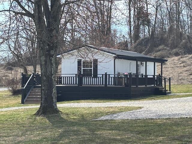 view of front of house featuring a front yard, a wooden deck, and metal roof