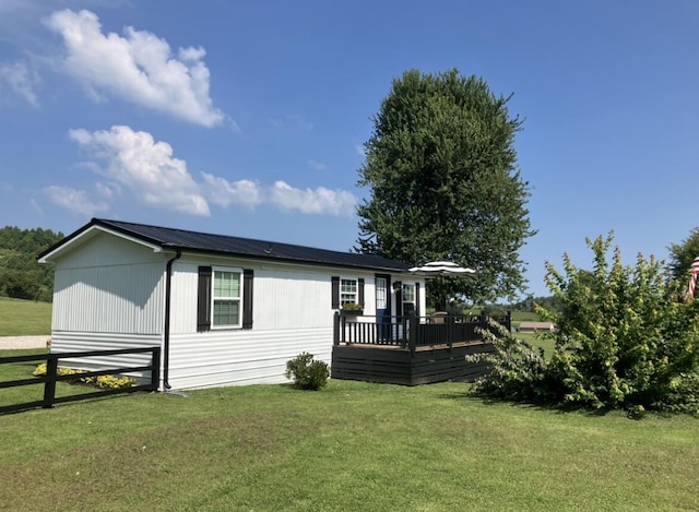 view of front of home featuring metal roof, a deck, a front lawn, and fence