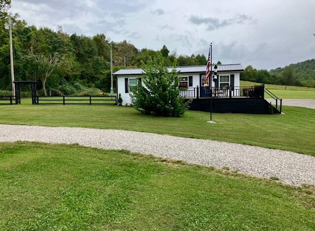 view of front facade with metal roof, a deck, a front yard, and fence