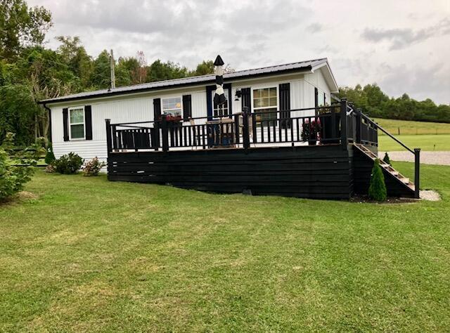 view of front of home featuring a wooden deck, metal roof, and a front yard