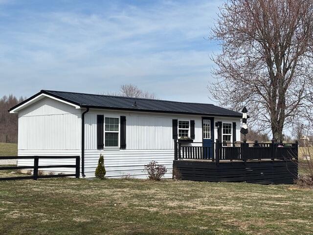 view of front of house featuring a deck, a front yard, fence, and metal roof