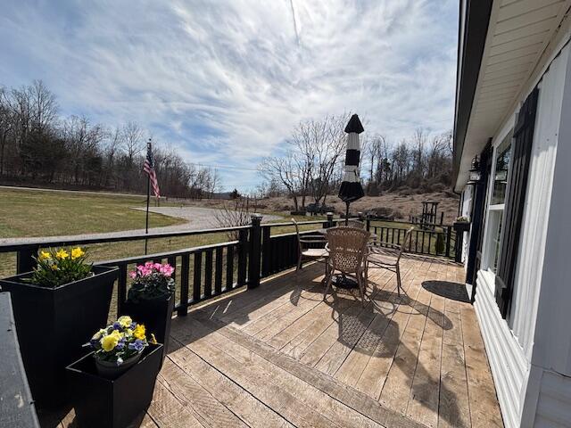 wooden deck featuring outdoor dining space and a lawn