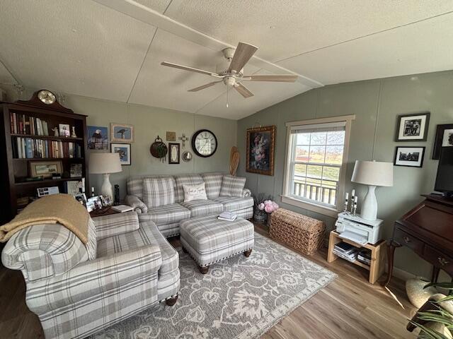 living area featuring a textured ceiling, wood finished floors, a ceiling fan, and vaulted ceiling