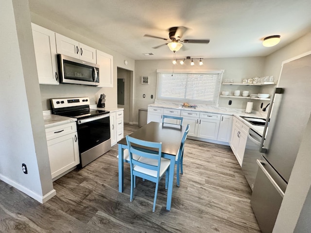 kitchen with white cabinetry, open shelves, wood finished floors, and appliances with stainless steel finishes