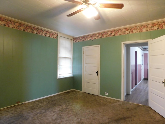 empty room featuring carpet flooring, a ceiling fan, baseboards, and ornamental molding