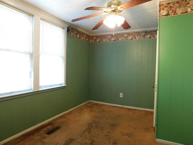 spare room with visible vents, crown molding, ceiling fan, baseboards, and carpet