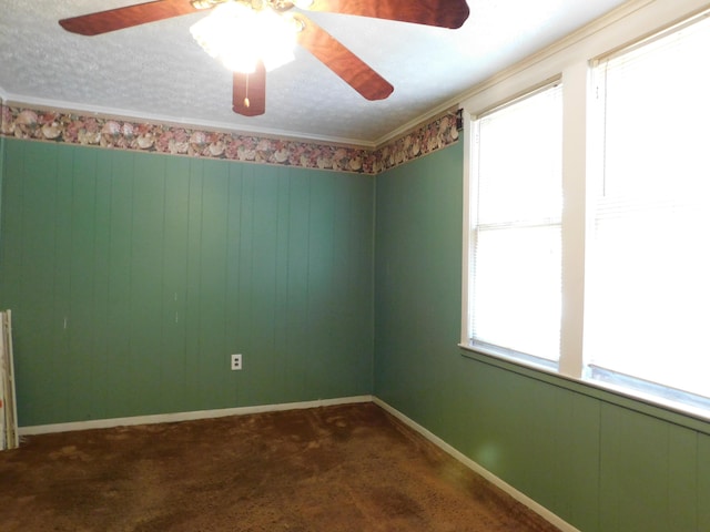 empty room featuring dark colored carpet, baseboards, a textured ceiling, and ornamental molding