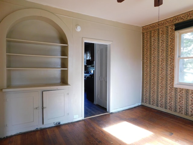 interior space featuring a ceiling fan, built in features, wood finished floors, and baseboards