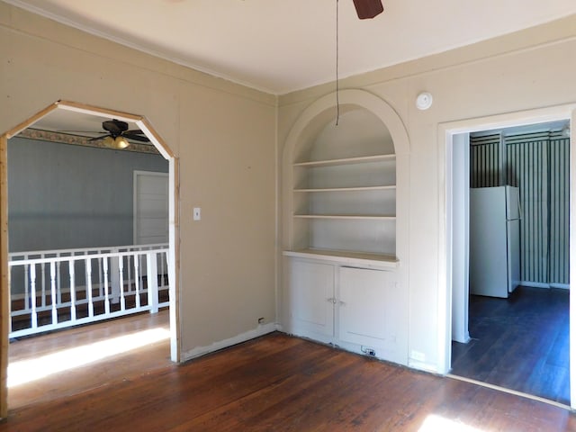 interior space with ornamental molding, built in shelves, ceiling fan, and wood finished floors