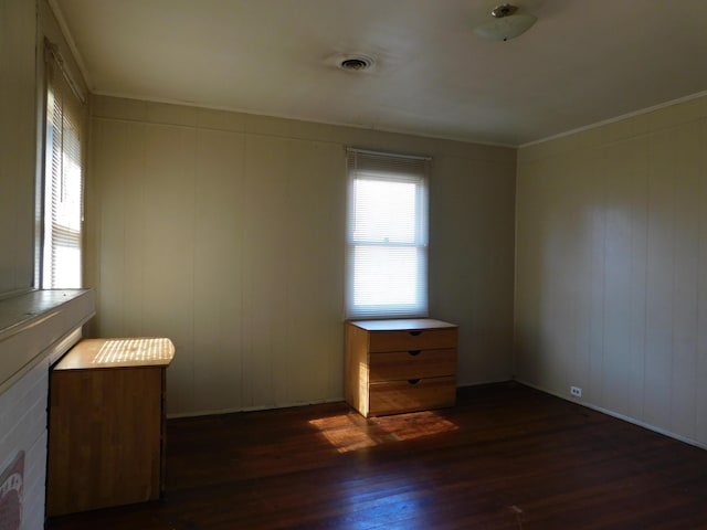 unfurnished bedroom featuring visible vents, ornamental molding, and dark wood-style flooring