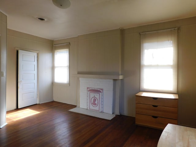 unfurnished living room with visible vents and dark wood-style floors