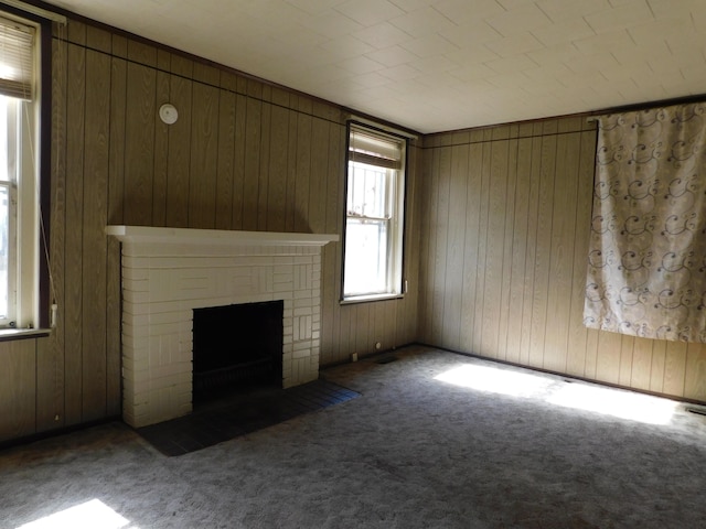 unfurnished living room featuring wooden walls, carpet flooring, and a fireplace