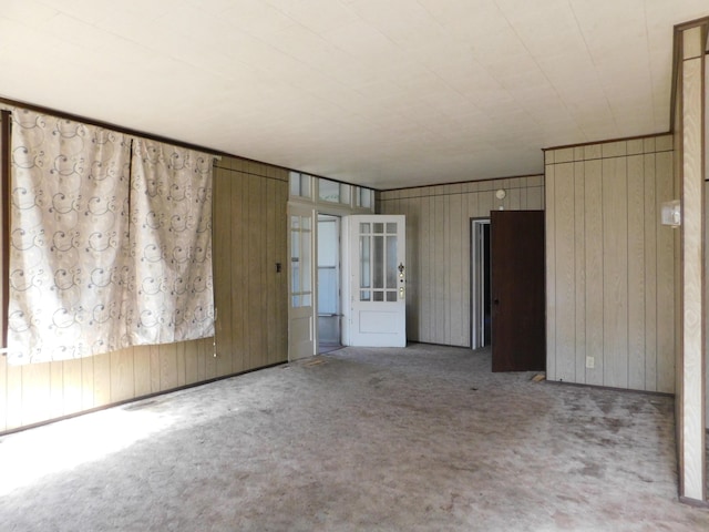 carpeted spare room featuring wood walls