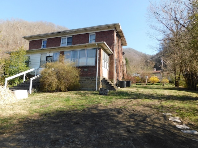 back of property featuring a yard, central AC unit, and brick siding