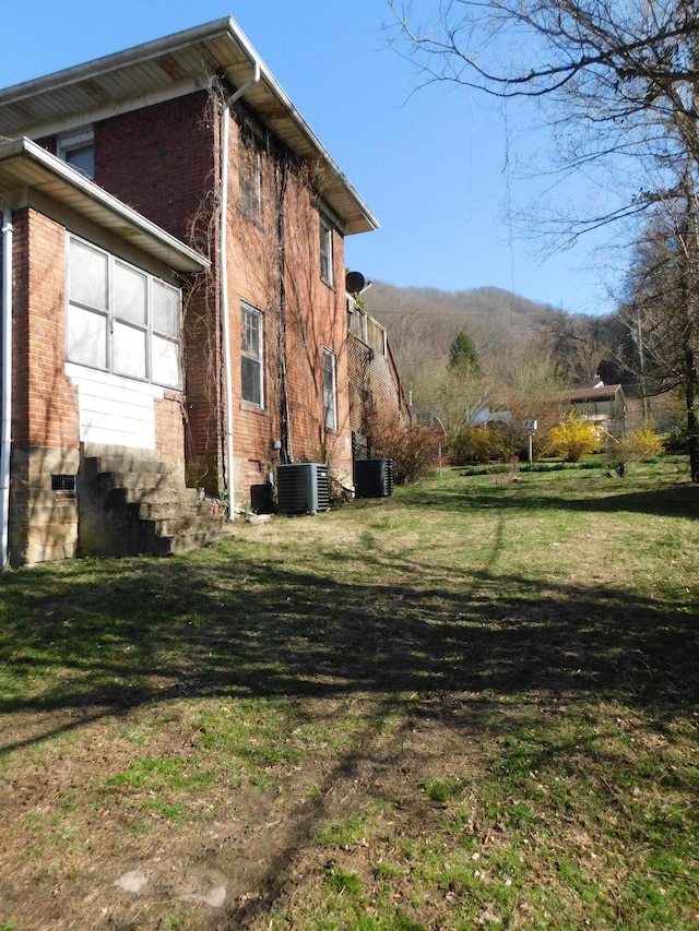 view of home's exterior featuring a yard, brick siding, and central AC