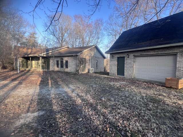 exterior space with ac unit, brick siding, and roof with shingles