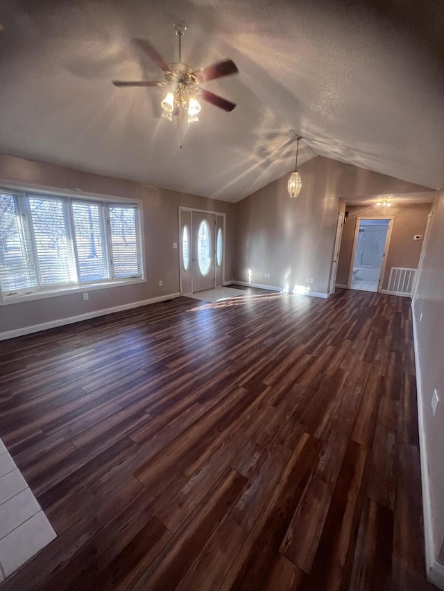 unfurnished living room with a ceiling fan, visible vents, baseboards, lofted ceiling, and dark wood-type flooring