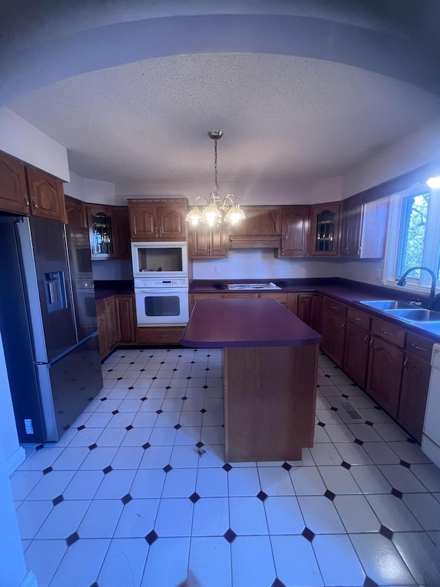 kitchen with a sink, white appliances, light floors, and a chandelier