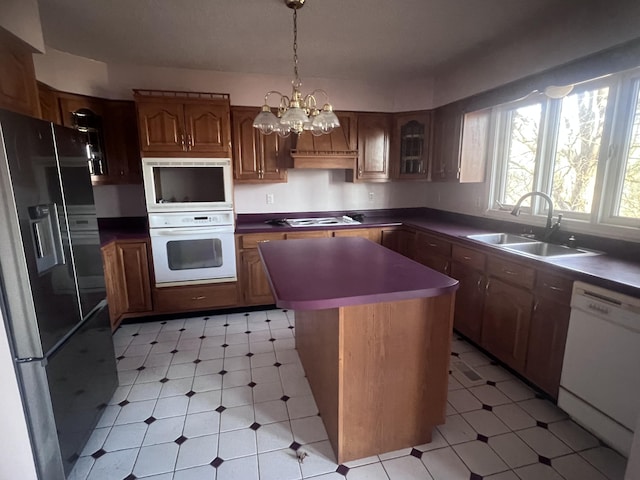 kitchen with white appliances, a center island, light floors, and a sink