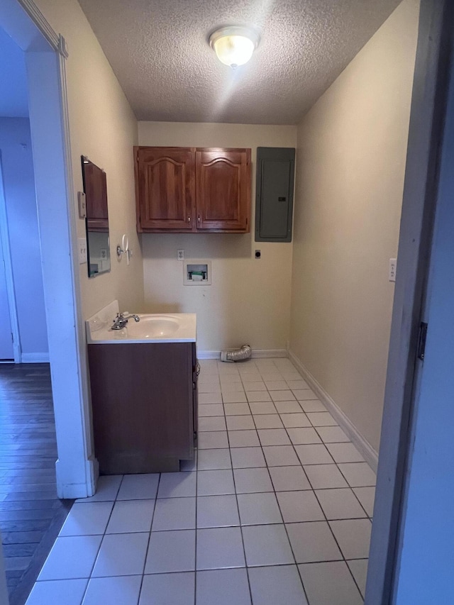 washroom featuring washer hookup, electric panel, a sink, light tile patterned flooring, and hookup for an electric dryer