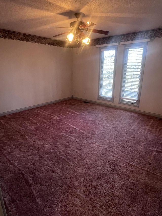 spare room featuring a textured ceiling, a ceiling fan, baseboards, and dark colored carpet