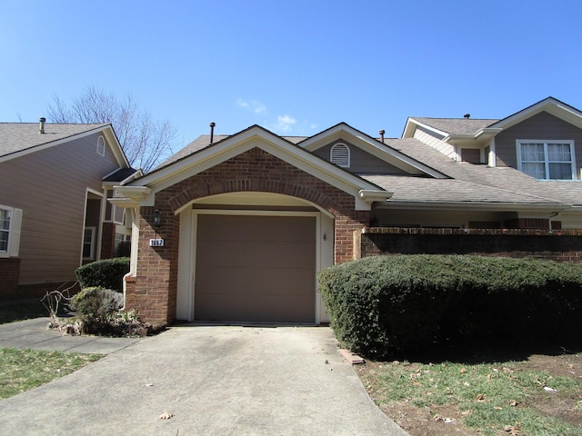 view of front of property with brick siding, an attached garage, concrete driveway, and a shingled roof