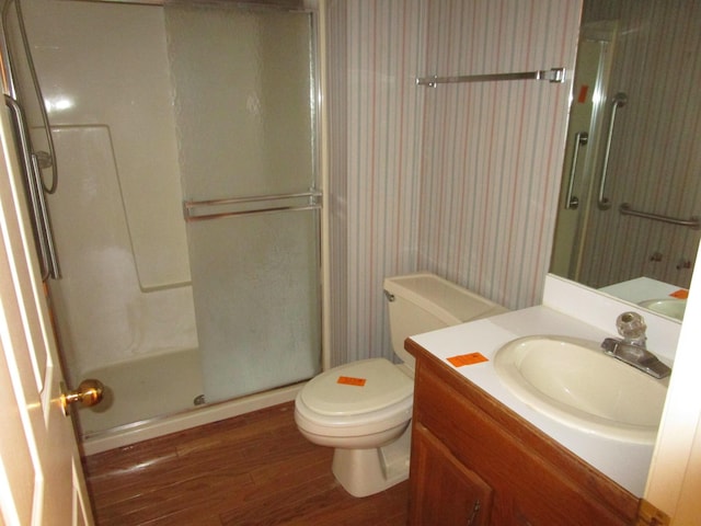 full bath featuring vanity, wood finished floors, a shower stall, and toilet