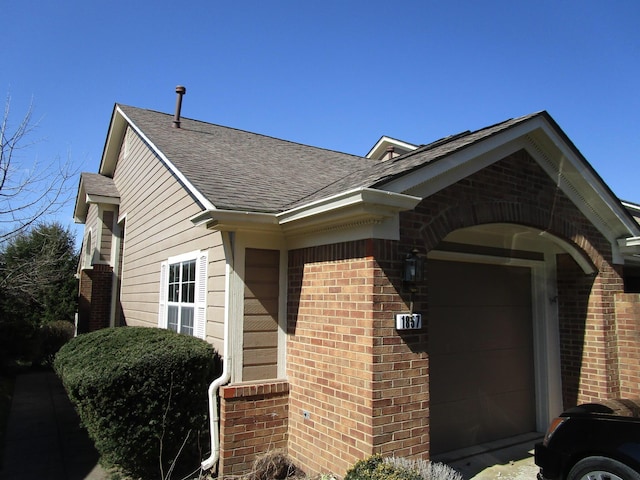 view of home's exterior featuring a garage, brick siding, and a shingled roof