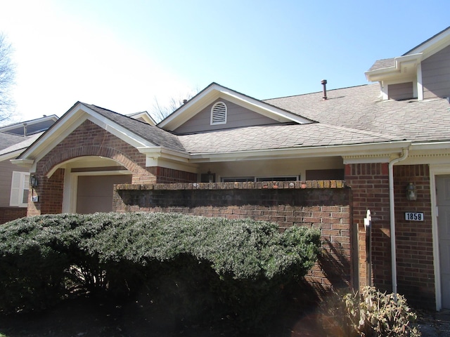 exterior space featuring brick siding and a shingled roof