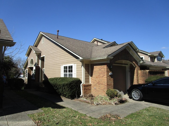 view of front facade featuring brick siding, an attached garage, and roof with shingles