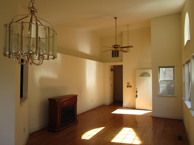 interior space with wood finished floors, visible vents, baseboards, ceiling fan, and a towering ceiling