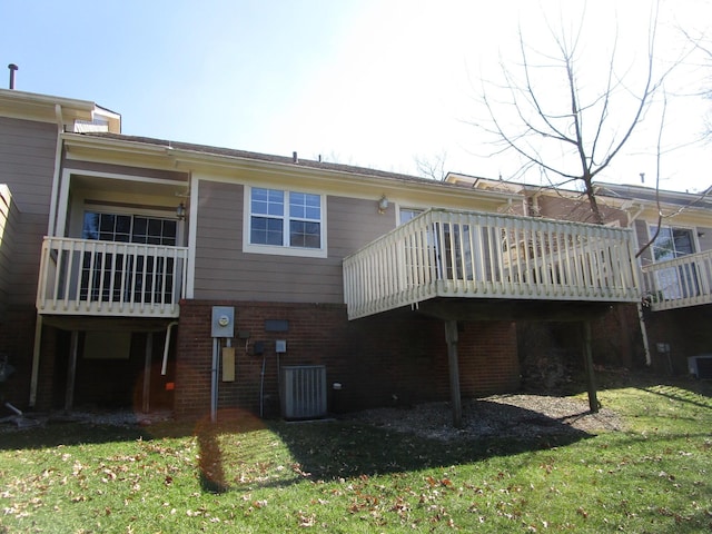 rear view of property featuring a deck, a yard, central AC unit, and brick siding