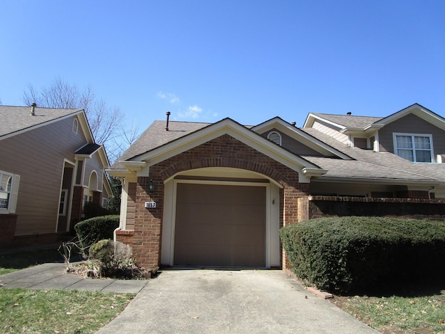 view of front of home featuring brick siding, driveway, a garage, and roof with shingles