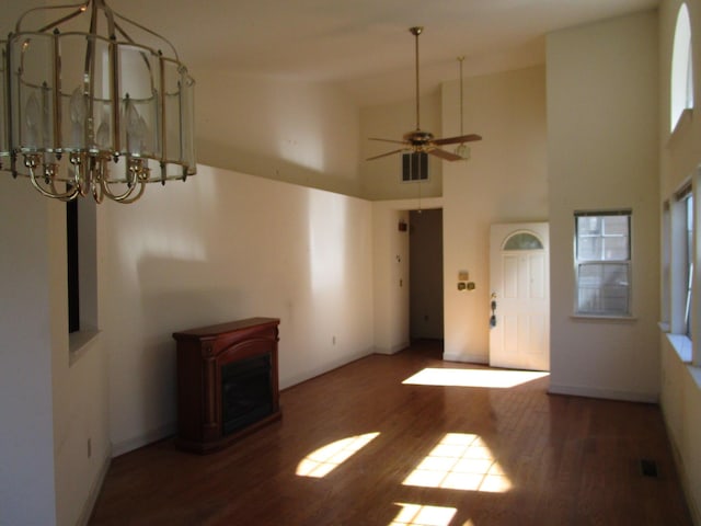 unfurnished living room featuring visible vents, ceiling fan, a towering ceiling, and wood finished floors