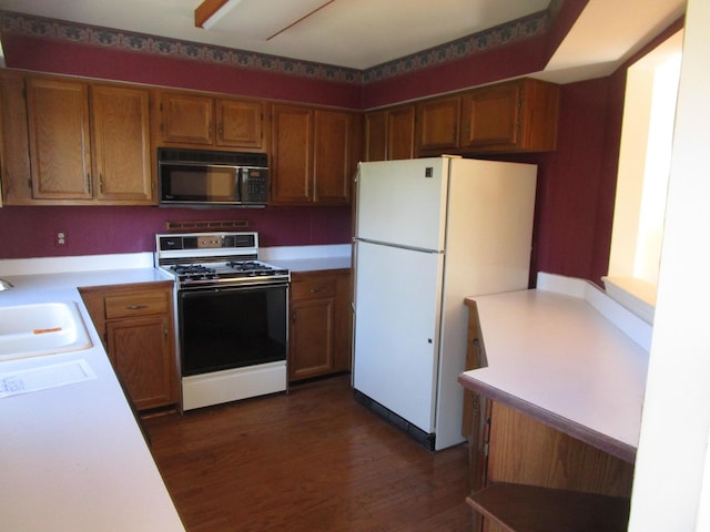 kitchen featuring gas stove, freestanding refrigerator, a sink, light countertops, and black microwave