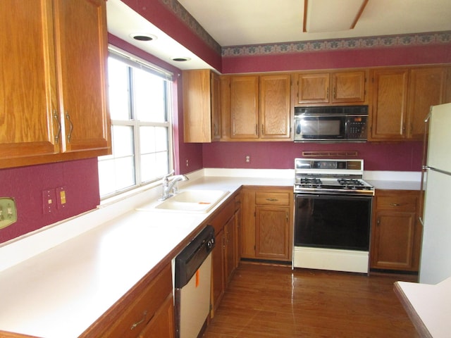 kitchen with white appliances, light countertops, brown cabinets, and a sink