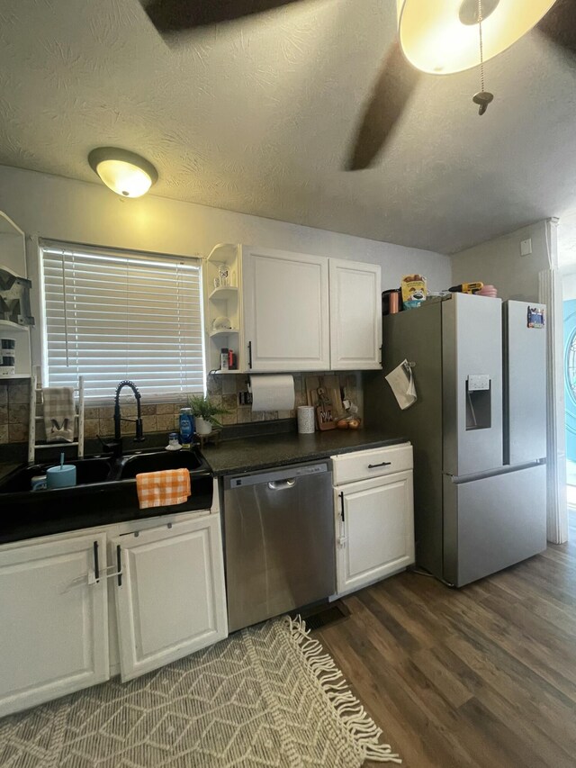 kitchen with open shelves, a sink, stainless steel appliances, white cabinetry, and dark countertops