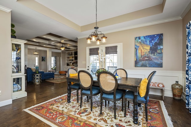 dining space featuring a raised ceiling, wood finished floors, coffered ceiling, and wainscoting