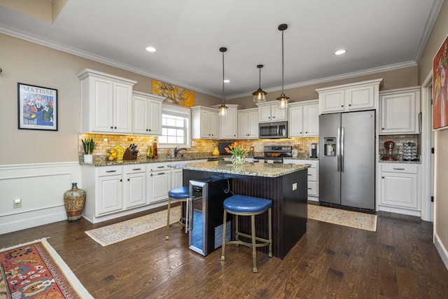 kitchen with a kitchen island, dark wood-type flooring, appliances with stainless steel finishes, white cabinetry, and crown molding