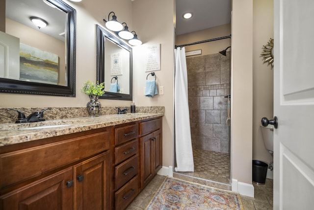 full bath with a sink, a tile shower, tile patterned flooring, double vanity, and baseboards