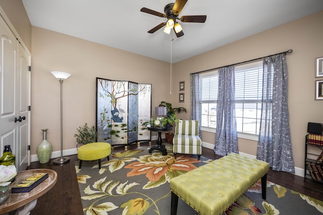 living area featuring wood finished floors, baseboards, and ceiling fan