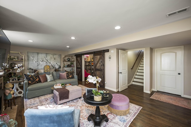 living area featuring visible vents, baseboards, stairway, a barn door, and wood finished floors