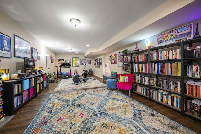 living area with wall of books, recessed lighting, and wood finished floors