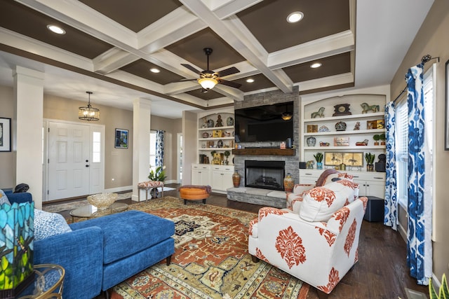 living area with a stone fireplace, coffered ceiling, a ceiling fan, and ornate columns