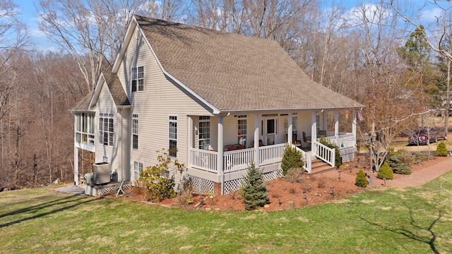 back of property with a yard, central air condition unit, a porch, and a shingled roof